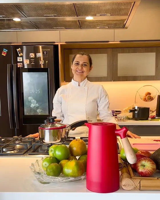 Elisabete de dólmã branca na cozinha de uma cliente, em dia de atendimento