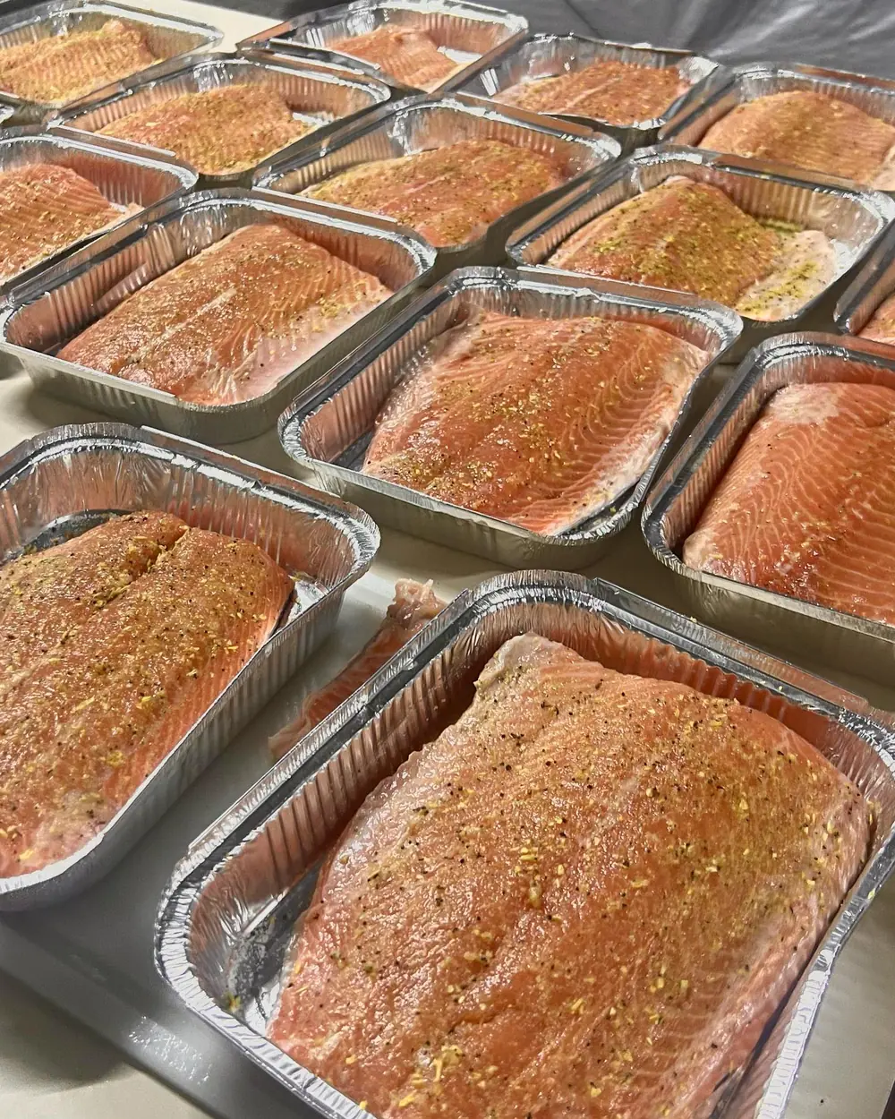 Dezenas de bandejas de salmão em crosta de ervas prontas para o evento