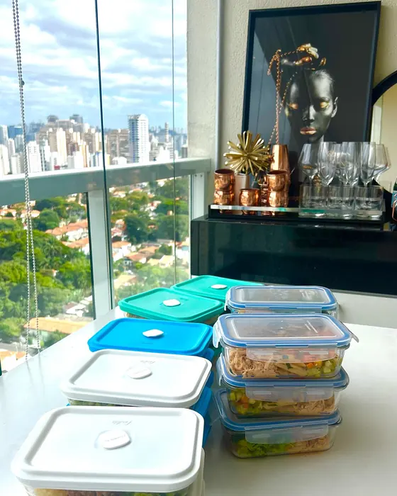 Potes de refeições prontas empilhados numa bancada com vista para a cidade